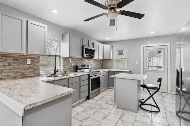 kitchen with gray cabinets, a wealth of natural light, appliances with stainless steel finishes, and a sink