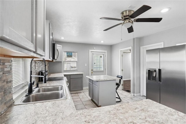 kitchen featuring marble finish floor, light countertops, a sink, appliances with stainless steel finishes, and ceiling fan