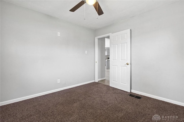 carpeted spare room with ceiling fan, baseboards, and visible vents