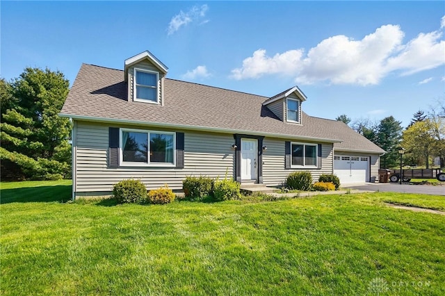 cape cod home featuring a garage, driveway, a front yard, and roof with shingles