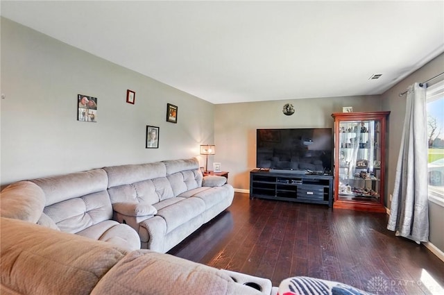 living area with hardwood / wood-style floors, visible vents, and baseboards