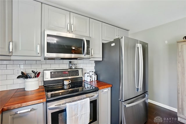 kitchen featuring wood counters, decorative backsplash, stainless steel appliances, and dark wood-type flooring
