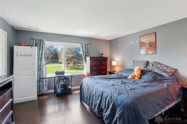 bedroom with baseboards, visible vents, and dark wood finished floors