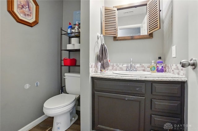 bathroom with decorative backsplash, toilet, vanity, and baseboards