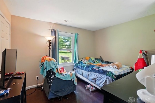 bedroom with visible vents, baseboards, and wood finished floors
