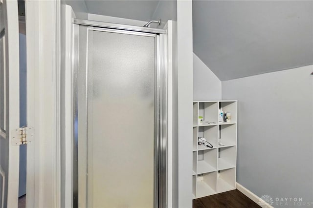 full bath with baseboards, lofted ceiling, wood finished floors, and a stall shower