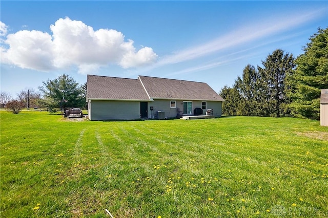 back of property with central air condition unit and a yard