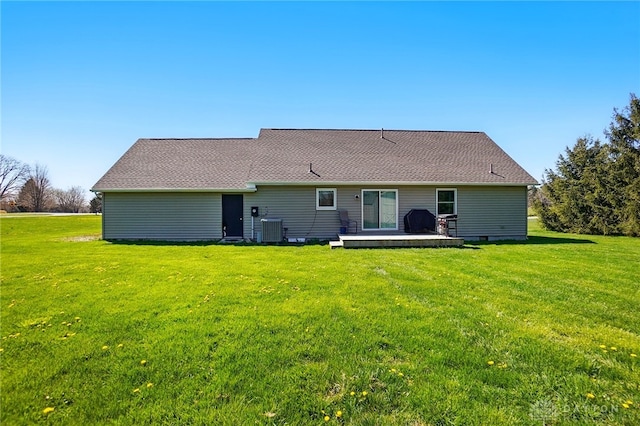rear view of property with a lawn, roof with shingles, and central AC