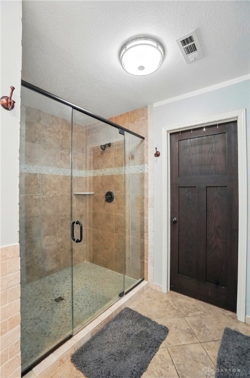 bathroom featuring a shower stall, a textured ceiling, and visible vents