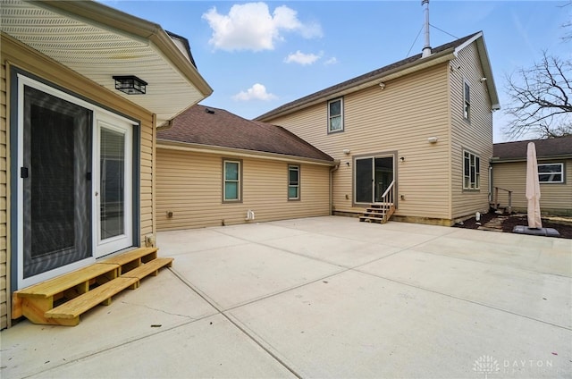 back of house with a patio area, entry steps, and roof with shingles