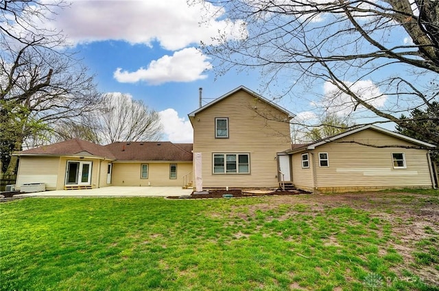 rear view of house featuring entry steps, a lawn, and a patio
