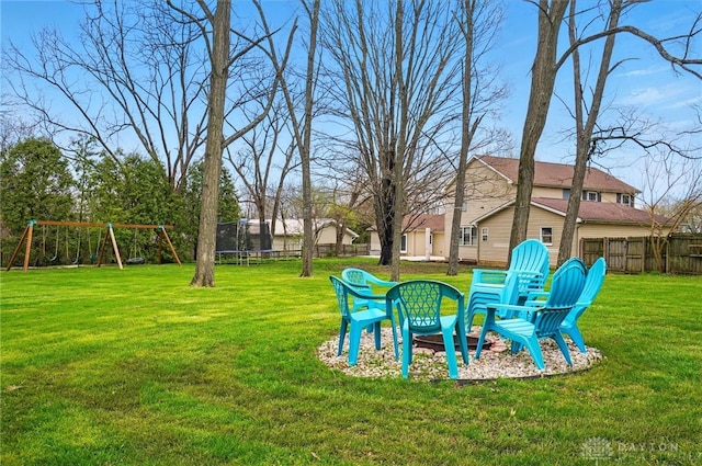 view of yard featuring fence, a playground, and a trampoline