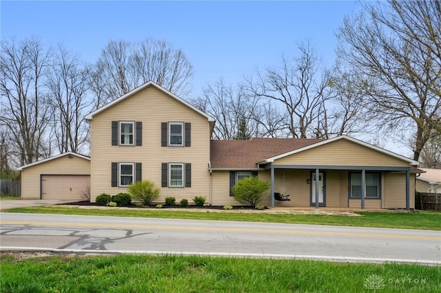 traditional home with covered porch, a garage, a shingled roof, an outdoor structure, and a front yard