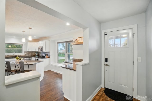 entryway with dark wood-type flooring, baseboards, and recessed lighting