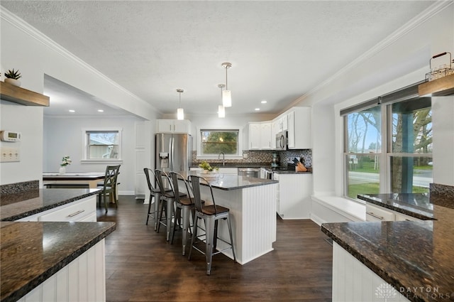 kitchen with a wealth of natural light, ornamental molding, stainless steel appliances, and dark wood-style flooring