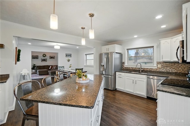 kitchen with a healthy amount of sunlight, appliances with stainless steel finishes, dark wood-style flooring, and a sink