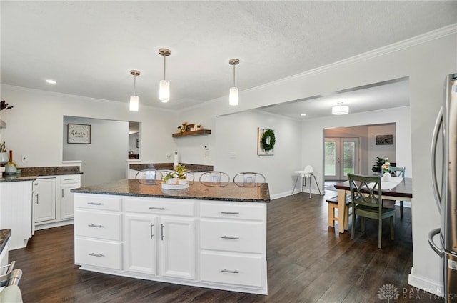 kitchen with pendant lighting, freestanding refrigerator, dark stone countertops, and dark wood finished floors