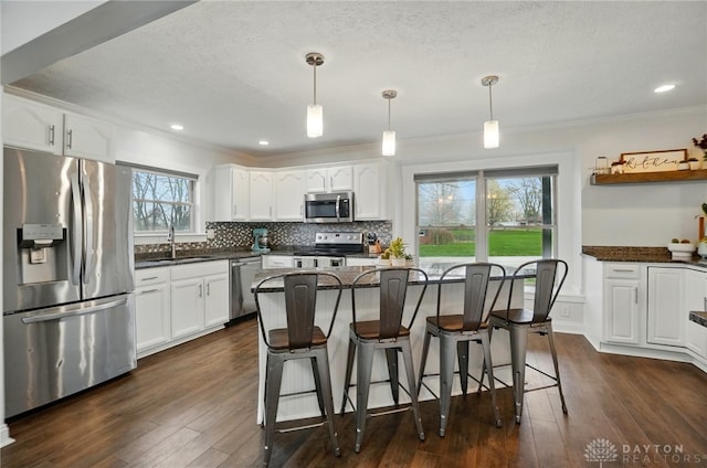 kitchen with white cabinets, stainless steel appliances, a sink, and ornamental molding