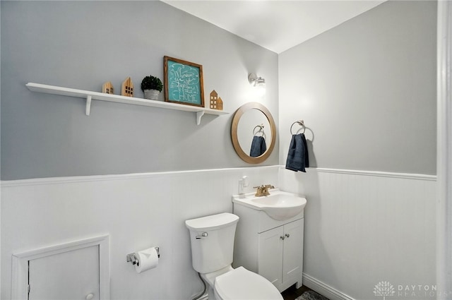 bathroom with a wainscoted wall, vanity, and toilet