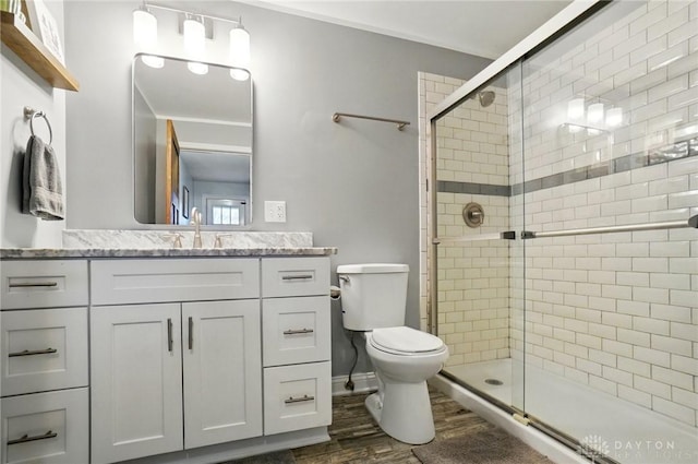 full bath with a shower stall, toilet, vanity, and wood finished floors