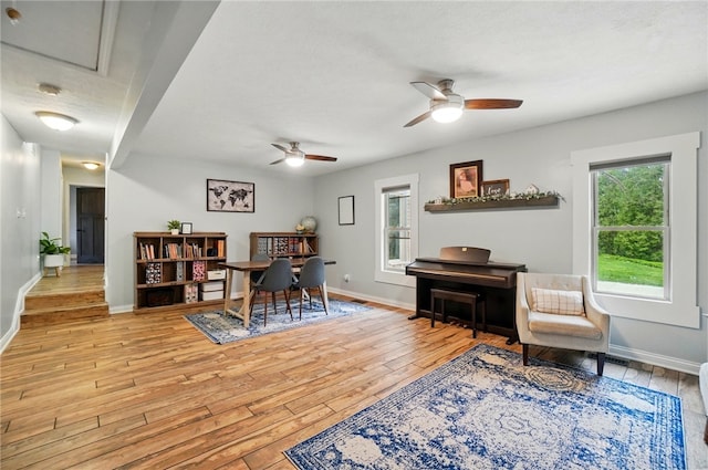 sitting room with light wood finished floors, a ceiling fan, and baseboards