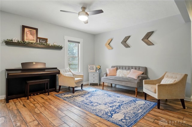 living area featuring wood-type flooring, baseboards, and ceiling fan