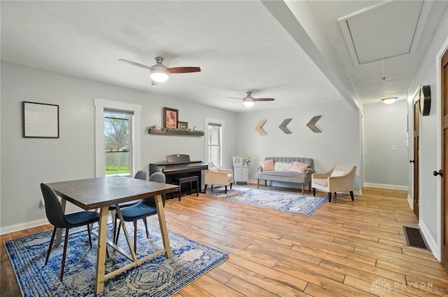 dining area featuring attic access, baseboards, visible vents, light wood-style floors, and ceiling fan