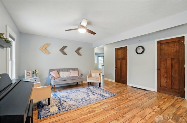 living room with hardwood / wood-style floors, visible vents, a ceiling fan, and baseboards