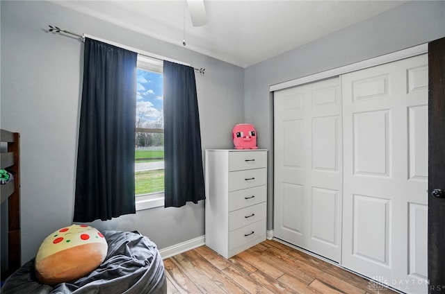bedroom with a closet, light wood finished floors, baseboards, and a ceiling fan