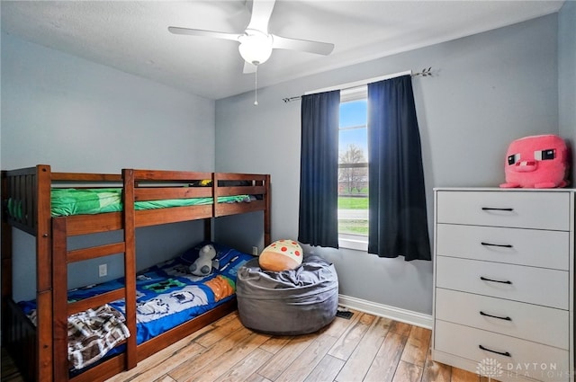 bedroom with wood finished floors, a ceiling fan, and baseboards