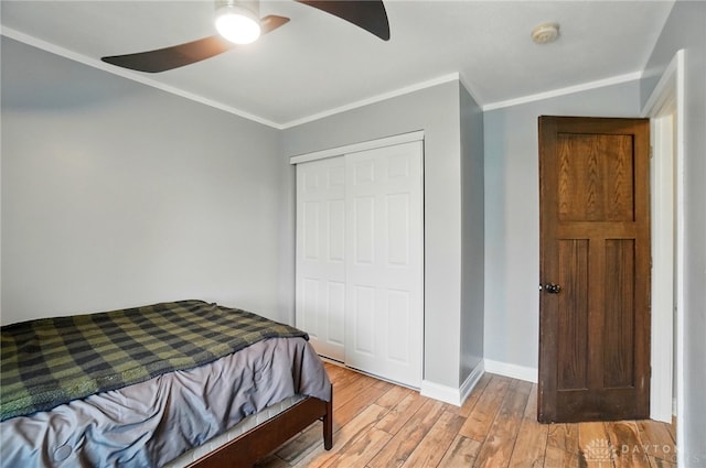 bedroom with a closet, light wood-type flooring, ceiling fan, baseboards, and ornamental molding