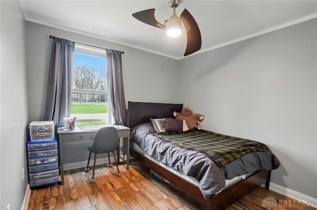 bedroom with baseboards, wood finished floors, ceiling fan, and crown molding