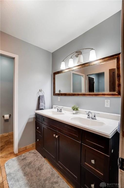 full bath with double vanity, tile patterned flooring, and a sink