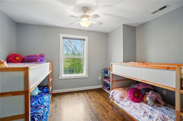 bedroom featuring baseboards, wood finished floors, visible vents, and ceiling fan