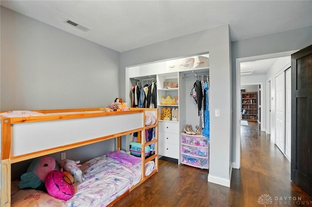 bedroom with baseboards, wood finished floors, visible vents, and a closet