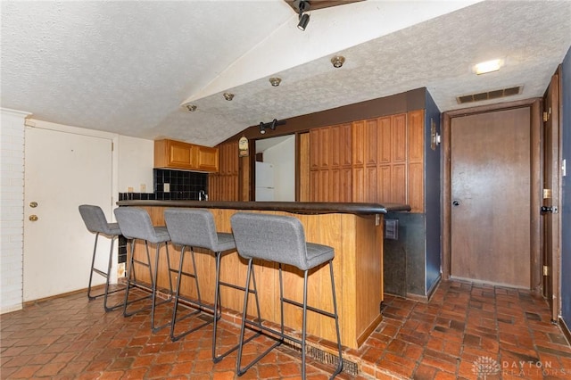 330 Rumson St, Englewood, OH 45322 - kitchen with a kitchen breakfast bar, a textured ceiling, lofted ceiling, visible vents, and freestanding refrigerator