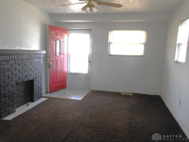 unfurnished living room with a ceiling fan, carpet flooring, a fireplace, and a healthy amount of sunlight