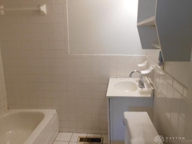 full bath with a wainscoted wall, visible vents, a washtub, vanity, and tile walls