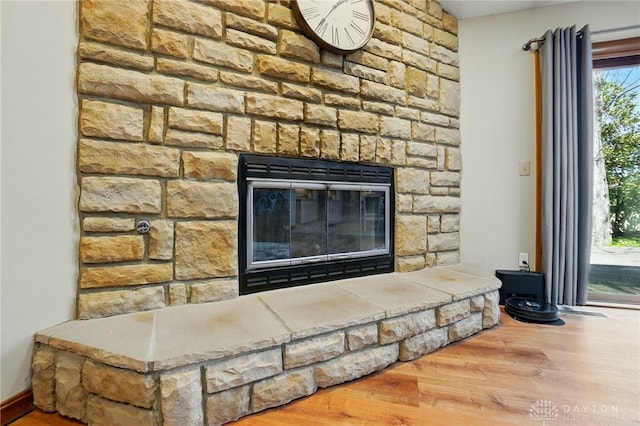 details featuring a stone fireplace and wood finished floors