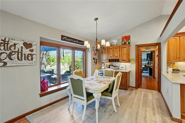 dining space with vaulted ceiling, light wood finished floors, baseboards, and a notable chandelier