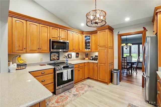 kitchen with brown cabinets, an inviting chandelier, pendant lighting, stainless steel appliances, and light wood-style flooring
