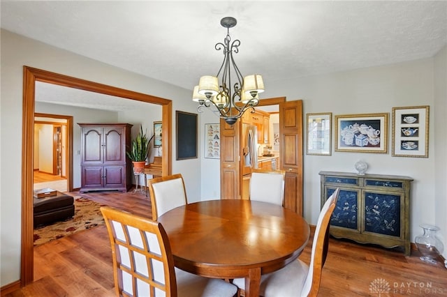 dining space featuring wood finished floors and an inviting chandelier