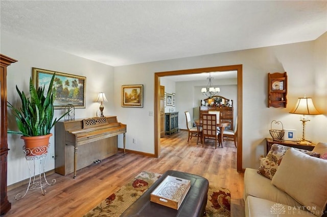 living room with baseboards, a notable chandelier, and wood finished floors