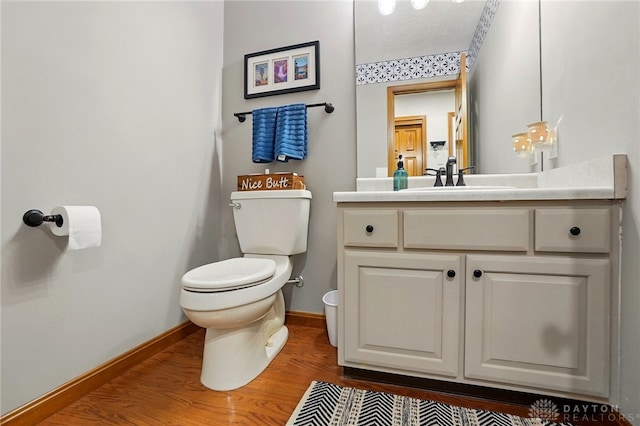 bathroom featuring baseboards, toilet, vanity, and wood finished floors