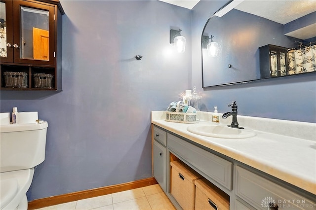bathroom with vanity, toilet, baseboards, and tile patterned floors