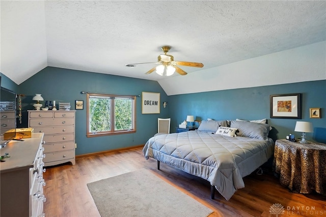 bedroom featuring lofted ceiling, wood finished floors, a textured ceiling, and ceiling fan