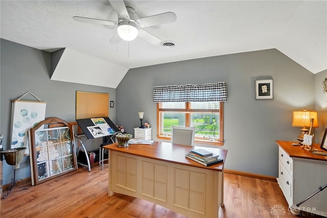 office area with vaulted ceiling, visible vents, a ceiling fan, light wood-style floors, and baseboards