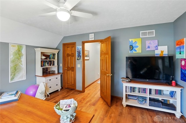 interior space featuring vaulted ceiling, wood finished floors, visible vents, baseboards, and ceiling fan