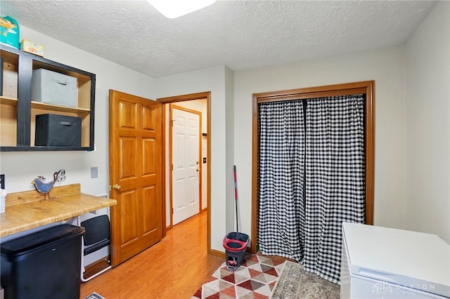 interior space featuring built in study area, a textured ceiling, and light wood finished floors