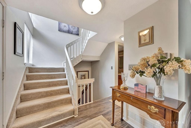 staircase with lofted ceiling and wood finished floors